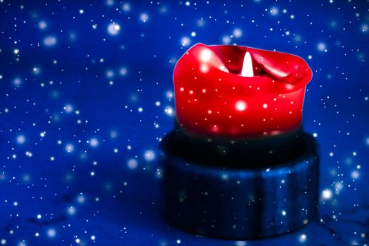 Happy holidays, greeting card and winter season concept - Red holiday candle on blue sparkling snowing background, luxury branding design for Christmas, New Years Eve and Valentines Day