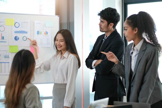 Female Operations Manager Holds Meeting Presentation for a Team of Economists. Asian Woman Uses Digital Whiteboard with Growth Analysis, Charts, Statistics and Data. People Work in Business Office..