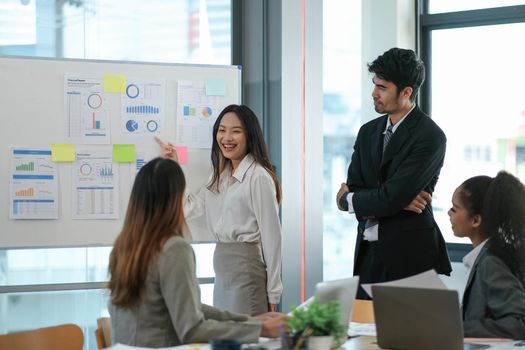 Female Operations Manager Holds Meeting Presentation for a Team of Economists. Asian Woman Uses Digital Whiteboard with Growth Analysis, Charts, Statistics and Data. People Work in Business Office..