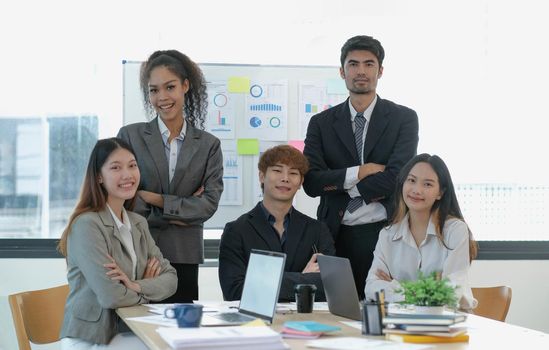 Asian business woman leader in a meeting with her multi-ethnic colleagues at the office presenting sales data or forecast for a project.