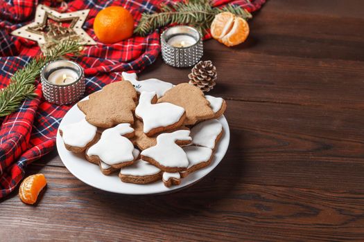 Delicious homemade Christmas cookies in the form of a rabbit and a Christmas tree on a wooden table decorated with New Year's decor. Copy spase