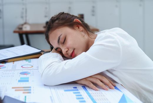 Portrait of a woman employee showing fatigue working on paperwork.