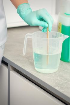 The beautician uses a stick to mix disinfectant into the water. Sterilization of tools