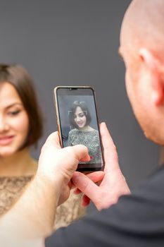 The hairdresser takes pictures of a woman finished short hairstyle on dark background