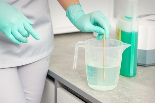 The beautician uses a stick to mix disinfectant into the water. Sterilization of tools