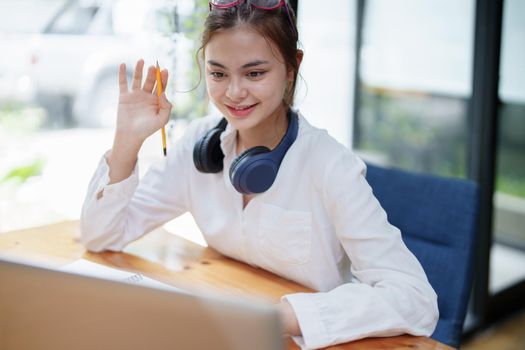 Portrait of a beautiful woman using a computer and earphone during a video conference