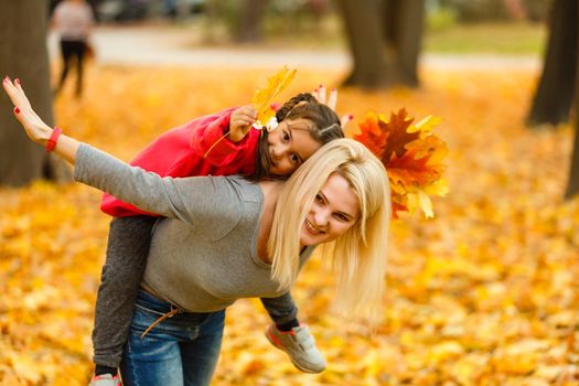 mother and daughter in the city park in autumn having fun time