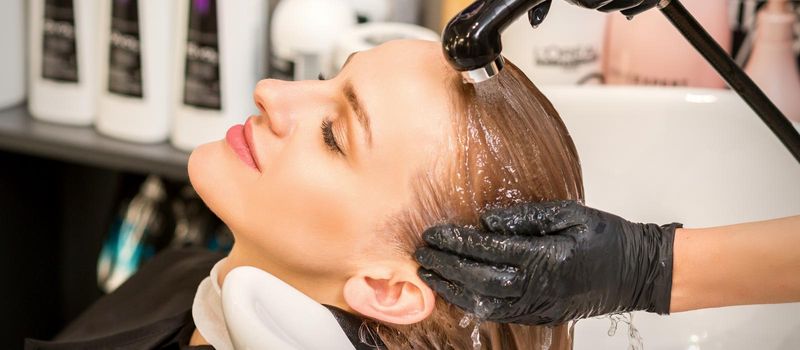 Young caucasian blonde woman having hair washed in the sink at a beauty salon