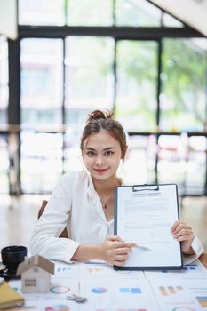 Portrait of a beautiful bank young woman sign credit department of signing approval for a home loan.