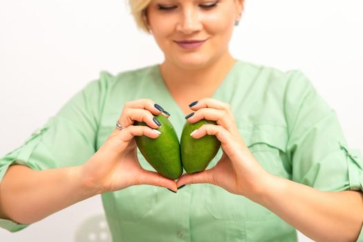 Female nutritionist doctor holding organic avocado fruit. Healthy lifestyle concept