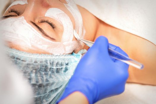Face peeling at the beautician. Facial treatment. The beautician applies a cleansing face mask to the female patient