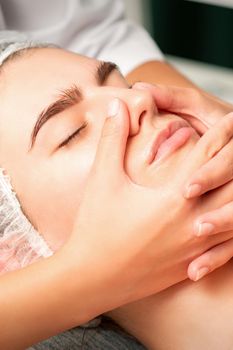 A young caucasian woman getting facial massage in a spa