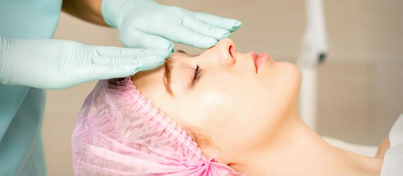 Face peeling at the beautician. Facial treatment. The beautician applies a cleansing face mask to the female patient