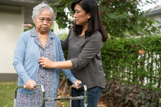 Caregiver help and care Asian senior or elderly old lady woman use walker with strong health while walking at park in happy fresh holiday.