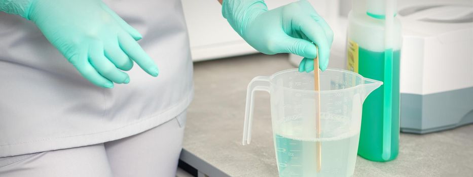 The beautician uses a stick to mix disinfectant into the water. Sterilization of tools