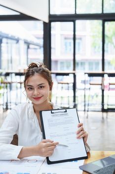 Portrait of a female business owner reading important documents before signing to verify approval of investment budget for their company.