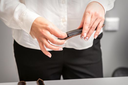 Manicured hands and tools for a manicure. Hands of manicurist take off instrument for a manicure from the leather case in a nail salon