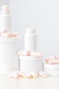 Cosmetic skincare packaging. Beauty product on white background. White jars with marshmallows on the white table