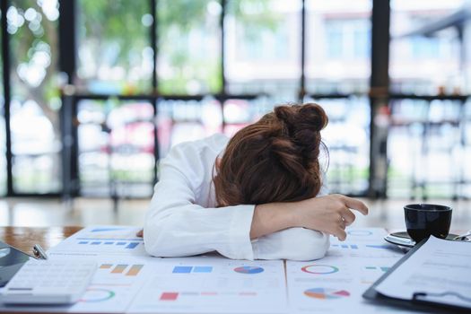 Portrait of a woman employee showing fatigue working on paperwork.