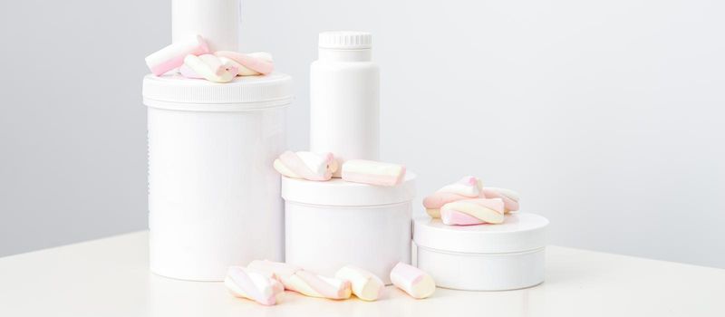 Cosmetic skincare packaging. Beauty product on white background. White jars with marshmallows on the white table