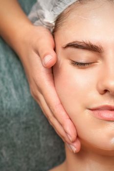 Spa facial skincare. Close-up of a young caucasian woman getting spa moisturizing face massage treatment at beauty spa salon