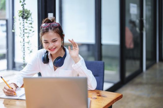 Portrait of a beautiful woman using a computer and a notebook during a video conference