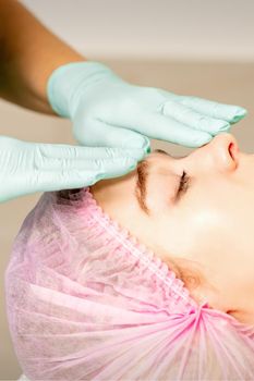 Face peeling at the beautician. Facial treatment. The beautician applies a cleansing face mask to the female patient