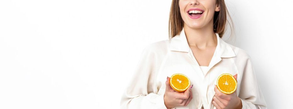 Joyful attractive young woman having two pieces of orange isolated on white background with copy space