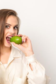 Diet nutrition. Beautiful young caucasian woman biting organic green avocado on white background. Healthy lifestyle, health concept