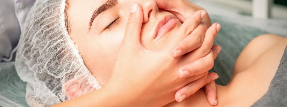 A young caucasian woman getting facial massage in a spa