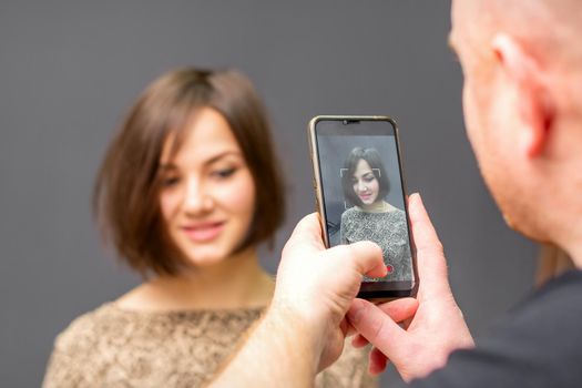 The hairdresser takes pictures of a woman finished short hairstyle on dark background