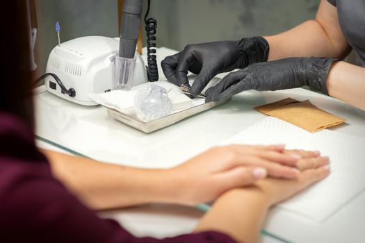 Hands in black gloves of manicurist preparing special nail file equipment for manicure treatment in a beauty salon