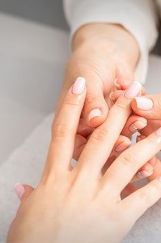 Manicure treatment at beauty spa. A hand of a woman getting a finger massage with oil in a nail salon