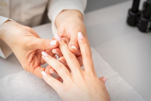 Manicure treatment at beauty spa. A hand of a woman getting a finger massage with oil in a nail salon