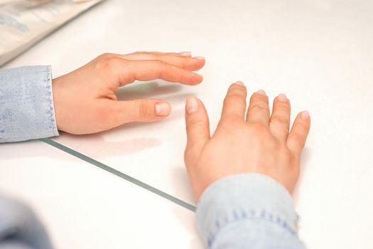 Hands of a young woman with well-groomed nails on the manicure table