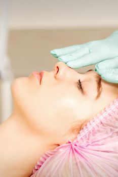 Face peeling at the beautician. Facial treatment. The beautician applies a cleansing face mask to the female patient