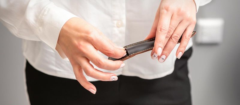 Manicured hands and tools for a manicure. Hands of manicurist take off instrument for a manicure from the leather case in a nail salon