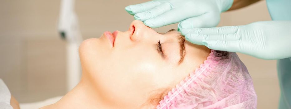 Face peeling at the beautician. Facial treatment. The beautician applies a cleansing face mask to the female patient