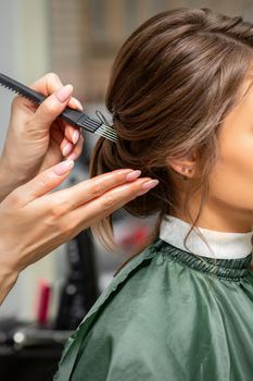 Makeup and hairstyle process. Makeup artist and hairdresser preparing young caucasian woman, working in tandem