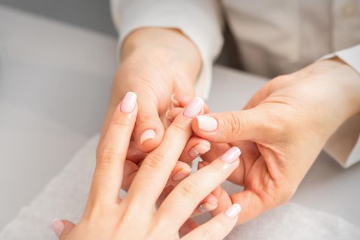 Manicure treatment at beauty spa. A hand of a woman getting a finger massage with oil in a nail salon