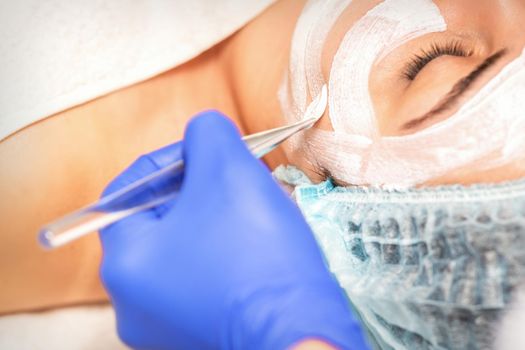 Face peeling at the beautician. Facial treatment. The beautician applies a cleansing face mask to the female patient