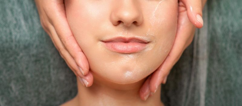 Spa facial skincare. Close-up of a young caucasian woman getting spa moisturizing face massage treatment at beauty spa salon