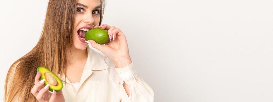 Diet nutrition. Beautiful young caucasian woman biting organic green avocado on white background. Healthy lifestyle, health concept