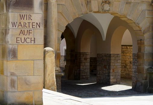 Detail of the old town hall of Bielefeld. In front is written on a pillar 'Wir warten auf euch'. This means : We wait for you. It's part of a memorial for the war prisoners in WWII