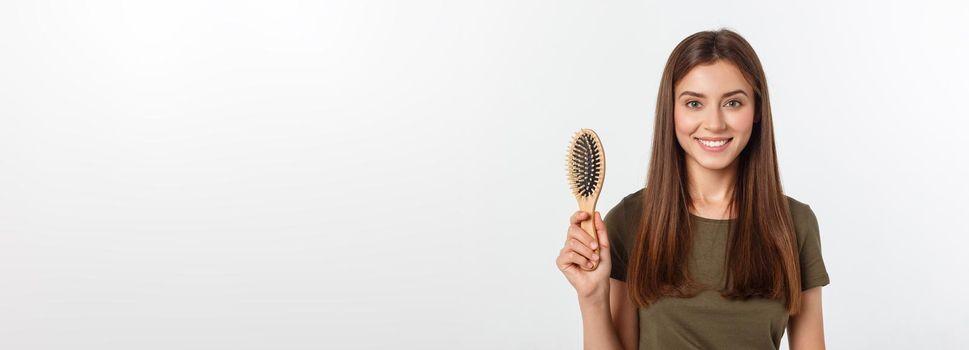 Happy young woman combing her long healthy hair on white background