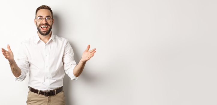 Surprised and happy businessman welcome you, looking excited and smiling, standing against white background.