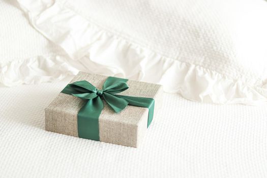 Holiday present and luxury online shopping delivery, wrapped linen gift box with green ribbon on bed in bedroom, chic countryside style, close-up