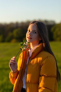 Portrait of a beautiful casual weared teenage girl outdoors in spring. A girl poses with blooming cherry brunch.