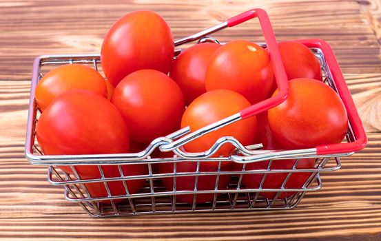 small cherry tomatoes in a grocery basket. On a wooden burnt background. The concept of buying vegetables from a farmer online. High quality photo