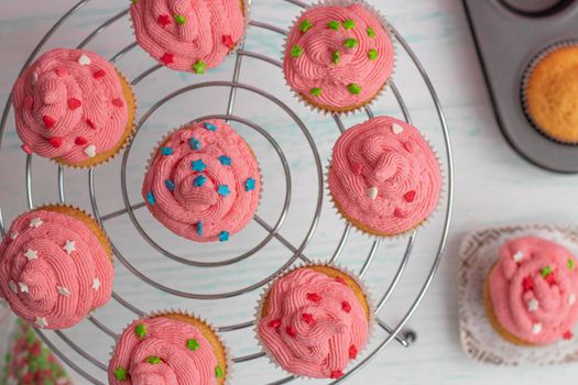 flatley muffins are decorated with bright pink cream and sugar decor. Stand on a spiral cooling rack. Homemade baking concept. Beautifully decorated cupcakes with butter cream. High quality photo